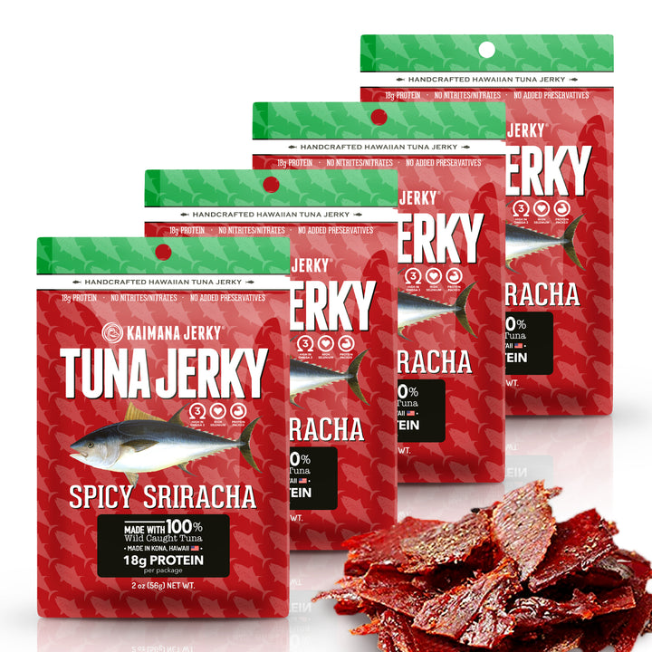 Four bags of Kaimana Jerky Spicy Sriracha tuna jerky arranged in a staggered stack, with several pieces of the red jerky meat displayed in front on a white background.